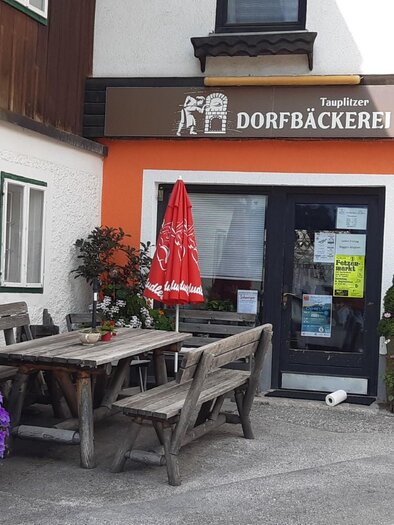Eine kleine Bäckerei mit einem einladenden Eingang und Tischen im Freien. Bunte Blumen schmücken den Bereich vor dem Geschäft. | © TVB Ausseerland Salzkammergut/Raunigg