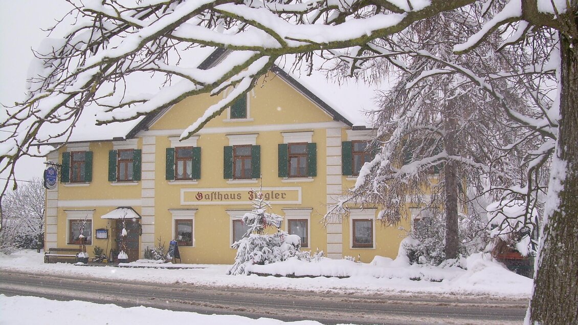 Ein gelbes Gebäude mit grünen Fensterläden im Schnee. Der Himmel ist grau und die Umgebung ist winterlich verschneit. | © Riedenbauer