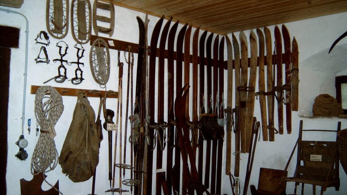 Eine Wand mit verschiedenen alten Skiern, Seilen und Werkzeugen. Die Gegenstände sind gut aufgereiht und zeigen eine rustikale Umgebung. | © Gemeinde Hirschegg-Pack
