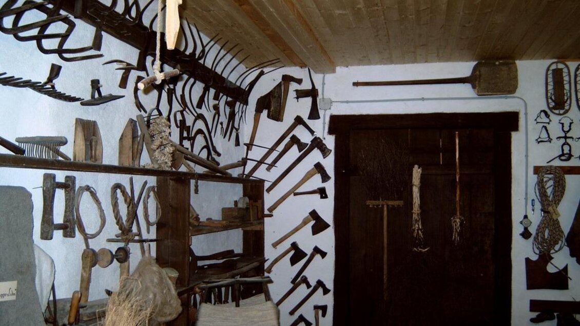 Ein Raum voller landwirtschaftlicher Werkzeuge und Geräte an den Wänden. Regale mit verschiedenen Handwerkszeugen sind gut sichtbar. | © Gemeinde Hirschegg-Pack