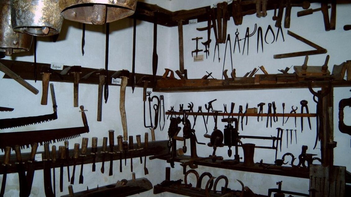 Eine Sammlung von alten Werkzeugen, die an Wänden und Regalen hängen. Die Werkstatt hat eine rustikale Atmosphäre mit vielen verschiedenen Handwerksinstrumenten. | © Gemeinde Hirschegg-Pack