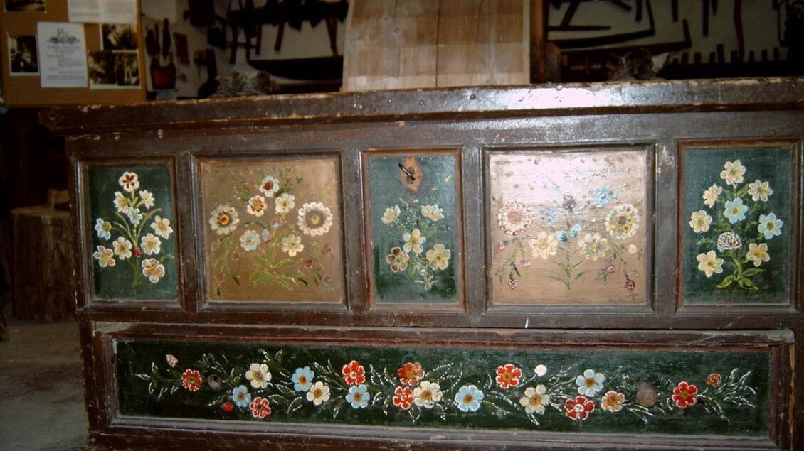 Ein kunstvoll bemalter Tisch mit blühenden Blumenmotiven. Die Farben sind lebhaft und verleihen dem Möbelstück eine charmante Note. | © Gemeinde Hirschegg-Pack