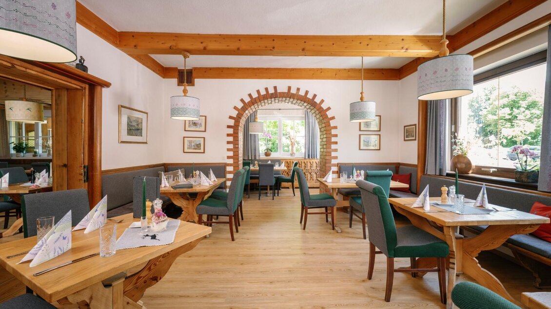 Ein einladendes Restaurant mit Holzmöbeln und einer warmen Atmosphäre. Die Tische sind liebevoll gedeckt, und große Fenster lassen viel Licht herein. | © Gasthaus Stöckl
