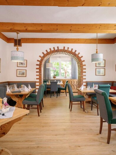 Ein einladendes Restaurant mit Holzmöbeln und einer warmen Atmosphäre. Die Tische sind liebevoll gedeckt, und große Fenster lassen viel Licht herein. | © Gasthaus Stöckl