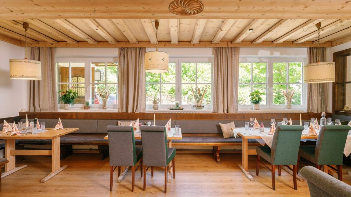 Ein gemütliches Restaurant mit Holzboden und Holzdecke. Tische sind für Gäste gedeckt, mit Blick auf Fenster und Pflanzen im Hintergrund. | © Gasthaus Stöckl