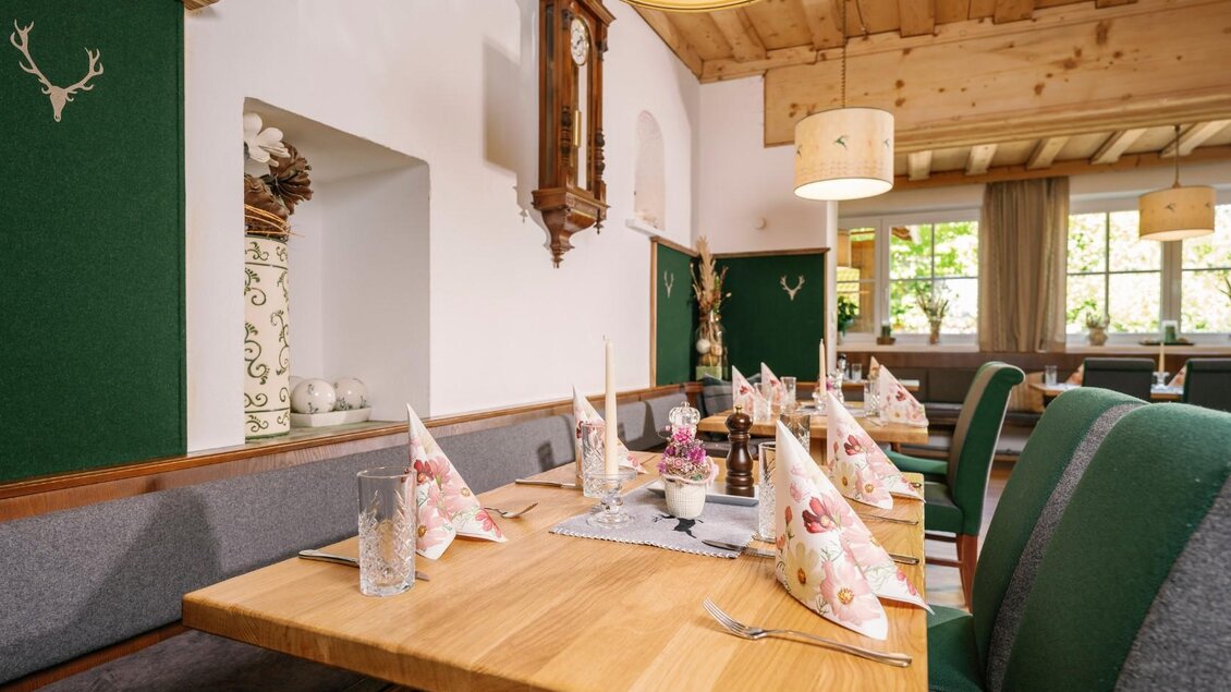 Ein gemütlicher Speiseraum mit Holzmöbeln und Tischdekoration in Form von Servietten. Große Fenster sorgen für eine helle und einladende Atmosphäre. | © Gasthaus Stöckl