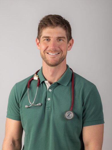 A young man with a stethoscope around his neck smiles kindly at the camera. He is wearing a green polo shirt and has a professional, friendly demeanor. | © Dr. Pintar Simon