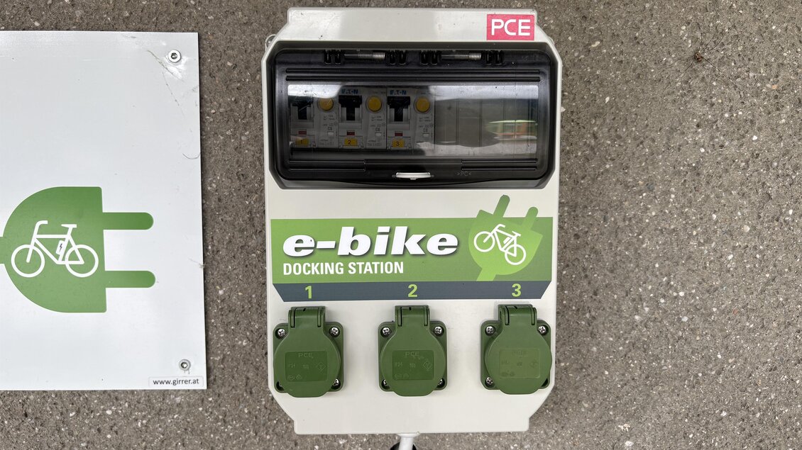 Eine E-Bike-Ladestation mit drei Anschlüssen. Sie ist auf einem asphaltieren Boden montiert und hat eine klare Beschilderung. | © TV Hochsteiermark, Leodolter