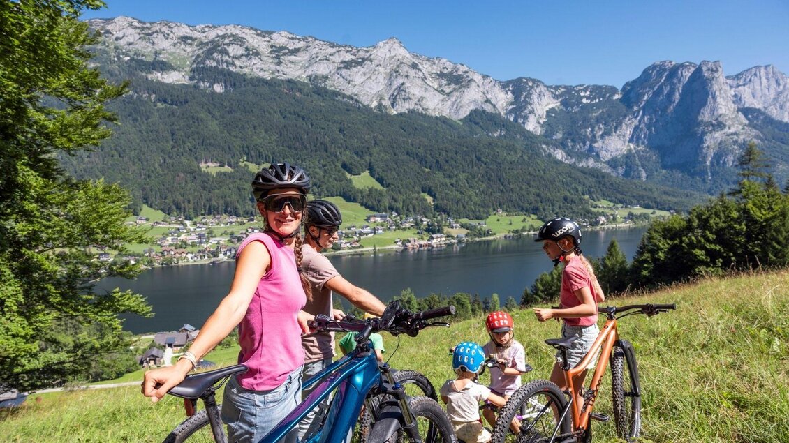 Eine Familie macht eine Fahrradtour in den Bergen. Im Hintergrund sieht man einen klaren See und eine beeindruckende Berglandschaft. | © www.zloam.at