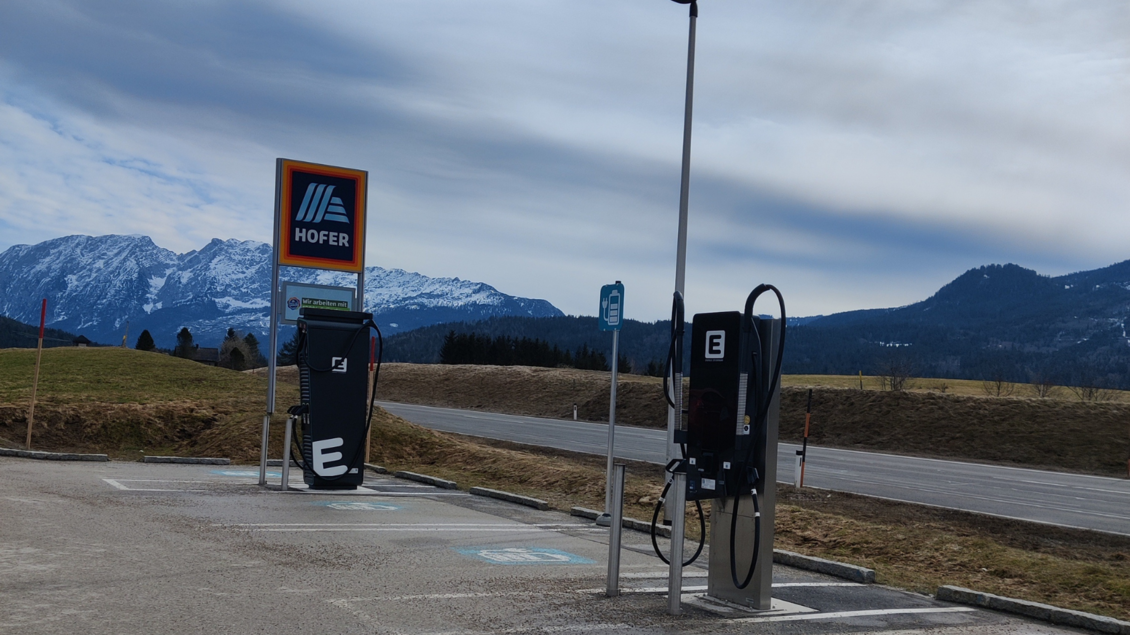 Ladestationen für Elektrofahrzeuge an einem Parkplatz. Im Hintergrund sind Berge und ein bewölkter Himmel zu sehen. | © TVB Ausseerland Salzkammergut (c) Michaela Schilcher