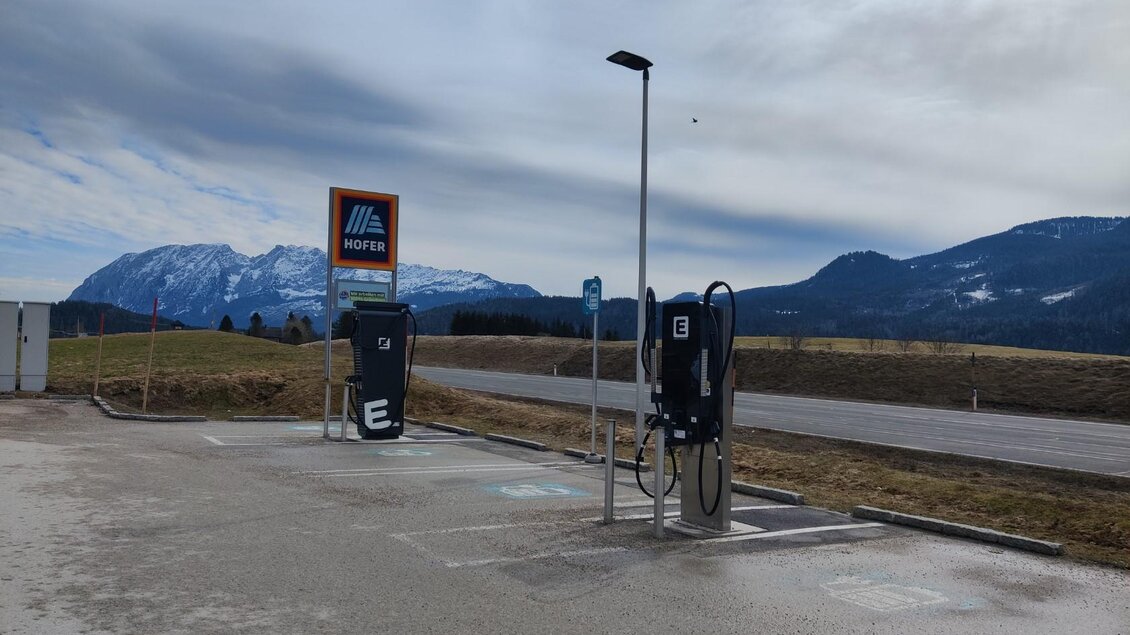 Eine Ladestation für Elektrofahrzeuge in einer ländlichen Umgebung, umgeben von Bergen. Der Himmel ist bewölkt und die Straße ist gut sichtbar. | © TVB Ausseerland Salzkammergut (c) Michaela Schilcher