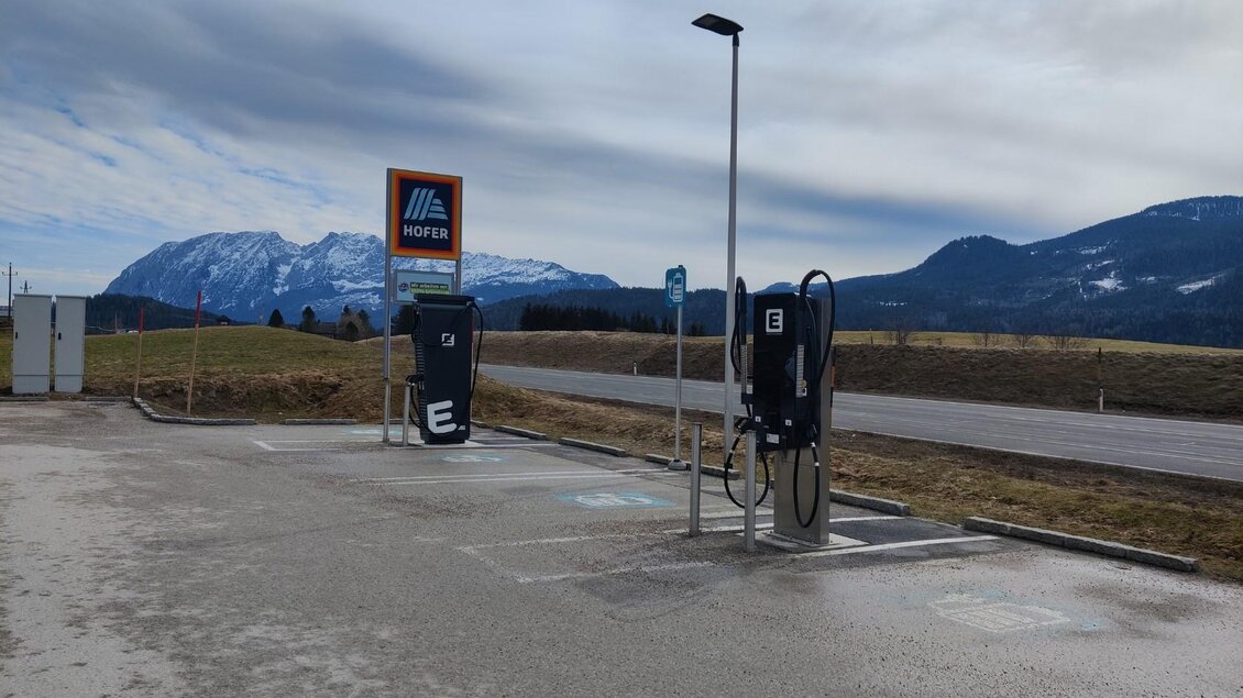 Eine moderne Elektro-Ladestation auf einem Parkplatz, umgeben von einer malerischen Berglandschaft. Der Himmel ist teilweise bewölkt und die Atmosphäre ist ruhig. | © TVB Ausseerland Salzkammergut (c) Michaela Schilcher