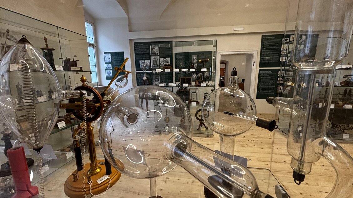 Ein Raum voller historischer wissenschaftlicher Apparate aus Glas. Im Hintergrund sind weitere Exponate und Informationen sichtbar. | © Echophysics