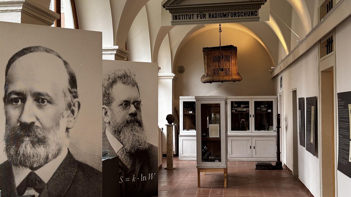 Ein Innenraum mit großen Portraits historischer Wissenschaftler. Im Hintergrund sieht man Ausstellungsstücke des Instituts für Klimaforschung. | © Echophysics