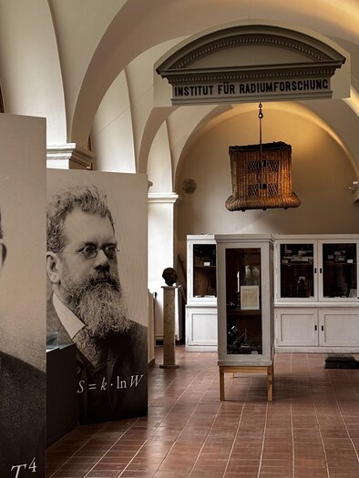 Ein Innenraum mit großen Portraits historischer Wissenschaftler. Im Hintergrund sieht man Ausstellungsstücke des Instituts für Klimaforschung. | © Echophysics