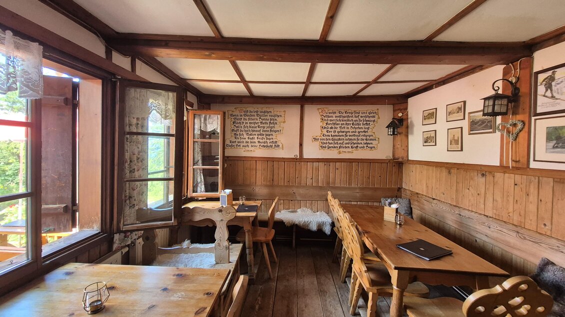 Ein gemütliches Restaurant mit Holztischen und Stühlen. An den Wänden hängen Bilder und Schriftzüge, die eine einladende Atmosphäre schaffen.
