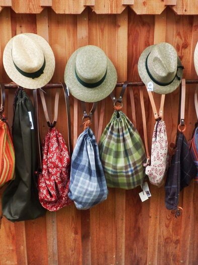 Eine Reihe von Hüten hängt an einer Holzlatte. Darunter sind verschiedene Taschen in bunten Mustern und Farben aufgehängt. | © Eva Eder
