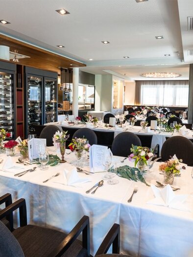 An elegant dining room with festively set tables and floral arrangements. The atmosphere is bright and inviting. | © Edler Landhaus Oswald