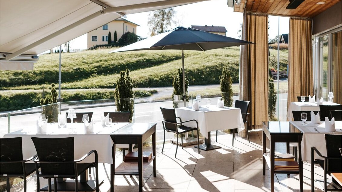 Ein elegantes Restaurant mit Tischen und Stühlen im Freien. Der Außenbereich ist hell und einladend, umgeben von einer schönen Landschaft. | © Edler Landhaus Oswald