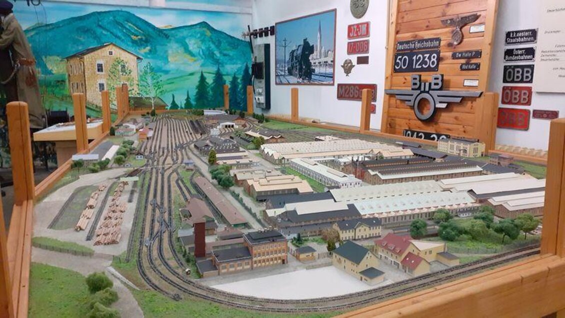 Eine detaillierte Modelllandschaft mit einer Eisenbahn und mehreren Gebäuden. Im Hintergrund sind Berge und verschiedene Schilder sichtbar. | © Erlebnisregion Murtal