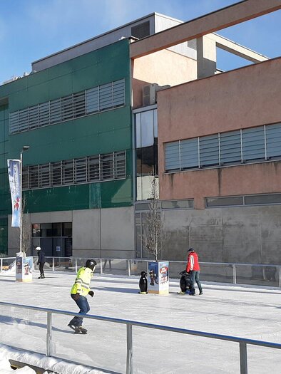 Eine Eislaufbahn vor einem modernen Gebäude. Menschen genießen das Schlittschuhlaufen bei klarem Wetter. | © Stadtgemeinde Köflach