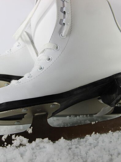 A pair of white ice hockey skates lies on a blanket of snow. The blades are smooth and shiny. | © Pixabay