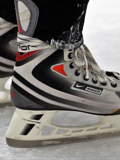 Ice skates on an ice surface. The skates are black and silver with red accents. | © Pixabay