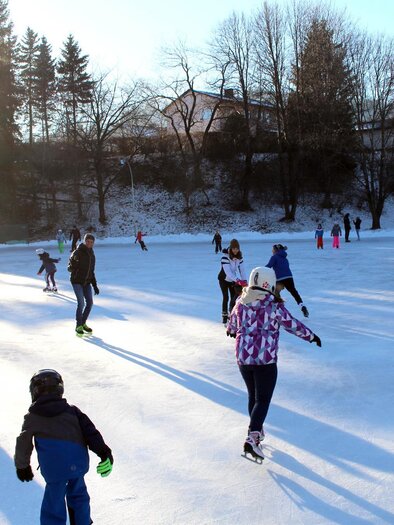 A group of people is ice skating on a frozen area. The sun is shining and the surroundings are wintry. | © Marktgemeinde Pöls-Oberkurzheim