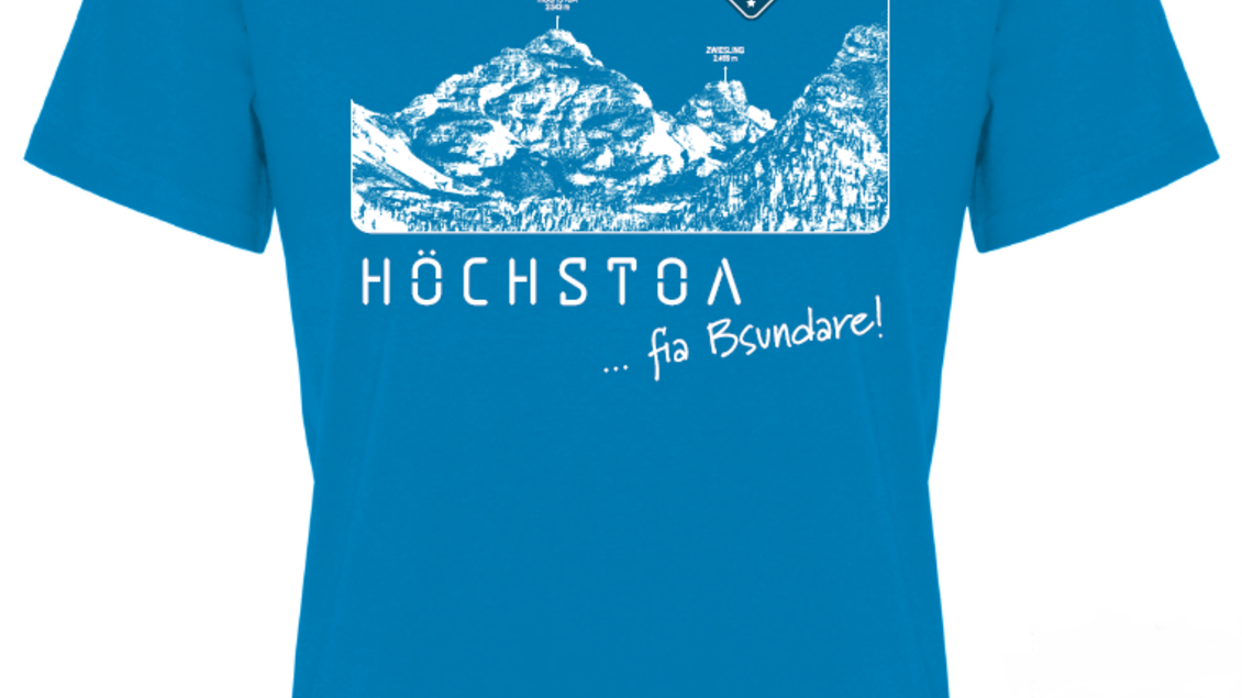 Ein leuchtend blaues T-Shirt mit einem grafischen Design von Bergen. Der Text "HÖCHSTOA ... fia B'sundare!" ist auffällig aufgedruckt. | © Eisleder Bergzeig