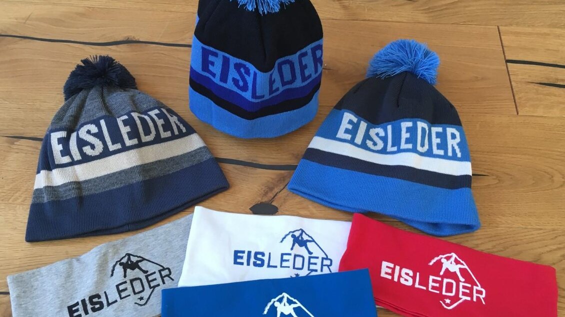 Ein Set von Mützen und Stirnbändern in verschiedenen Farben. Alle sind mit dem Logo "EISLEDER" bedruckt. | © Eisleder Bergzeig