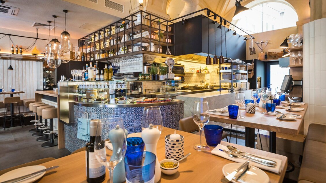 Ein modernes Restaurant mit einer stilvollen Bar und blauen Dekorationselementen. Die Tische sind für Gäste gedeckt und die Atmosphäre ist einladend. | © El Pescador - Werner Klug