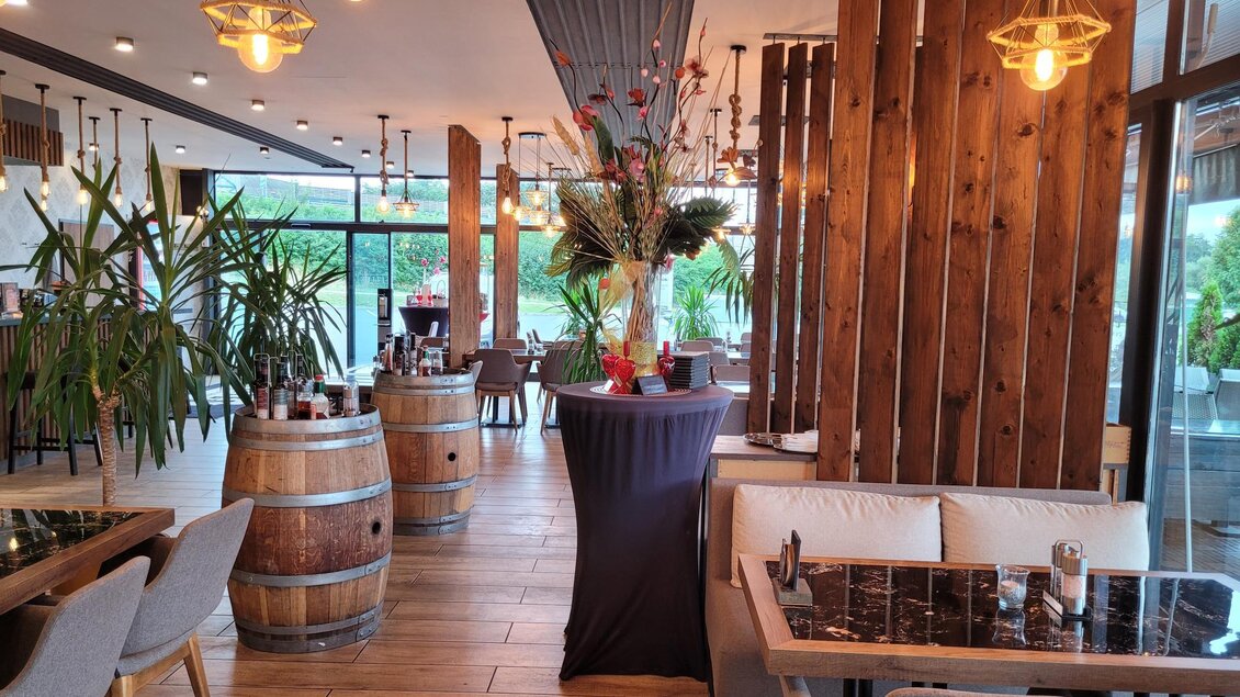 Ein modernes Restaurant mit Holzverkleidung und stilvollen Möbeln. Grüne Pflanzen und dekorative Elemente schaffen eine einladende Atmosphäre. | © TV Südsteiermark - Irene Löschnig