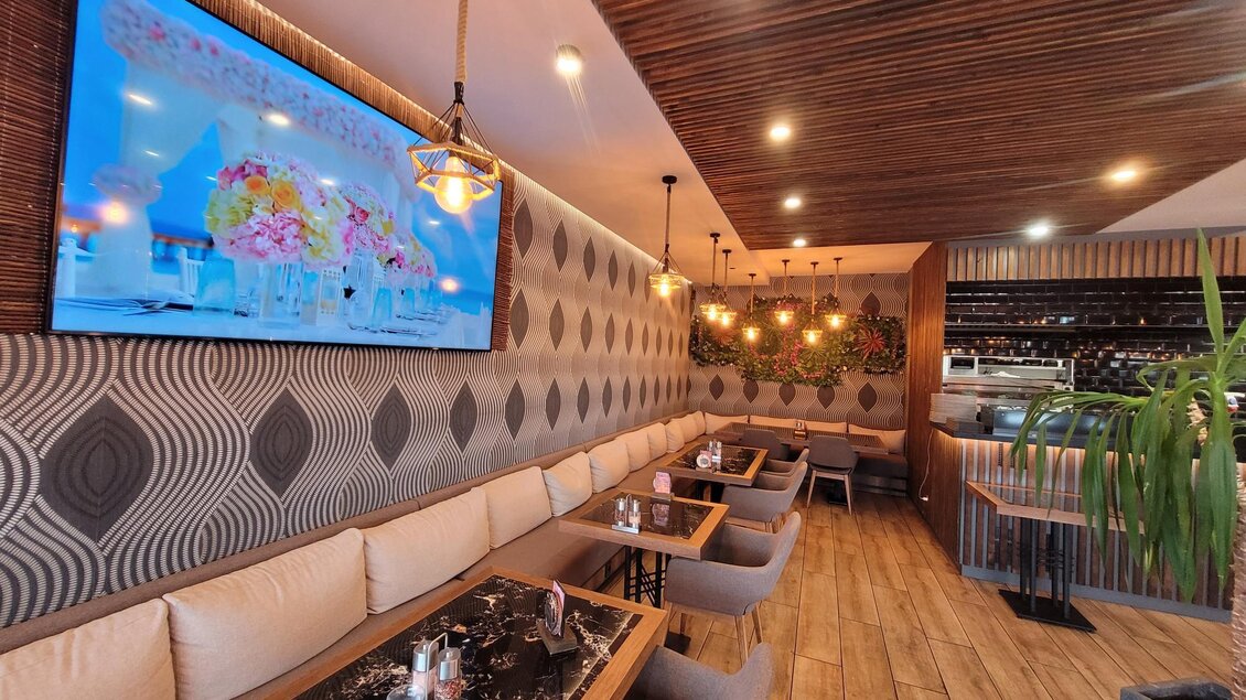 Ein modernes Restaurant mit eleganter Einrichtung und gemütlichen Sitzplätzen. An der Wand hängt ein großer Fernseher, und die Atmosphäre ist einladend. | © TV Südsteiermark - Irene Löschnig