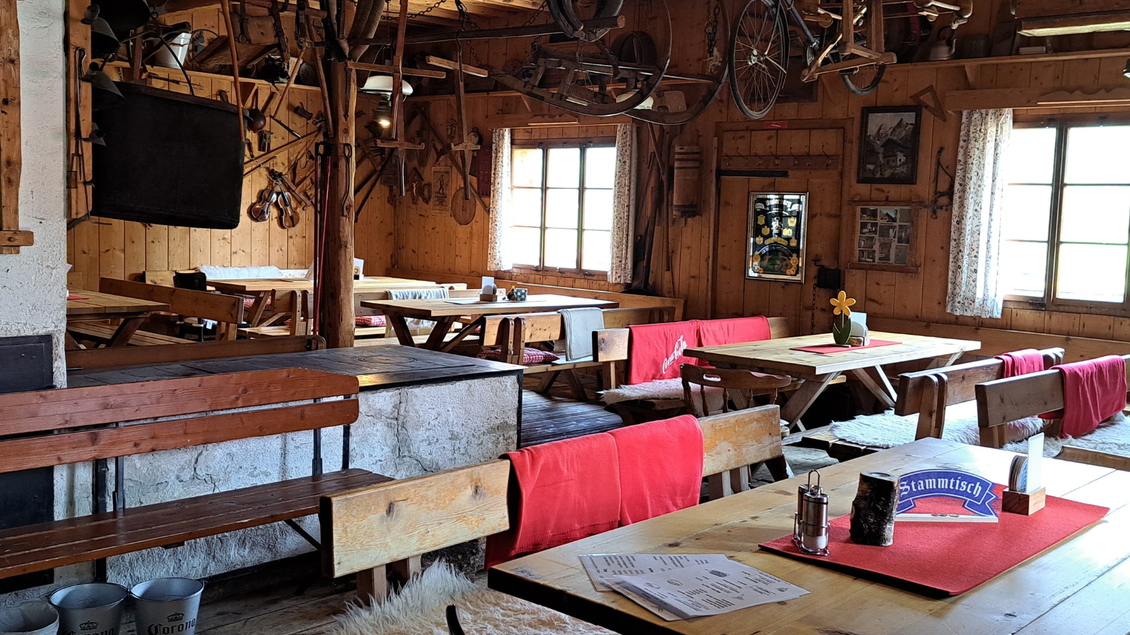 Eine gemütliche Stube mit Holzmöbeln und rustikaler Dekoration. Auf den Tischen liegen Menükarten und ein Blumentopf sorgt für freundliche Atmosphäre. | © Eselalm