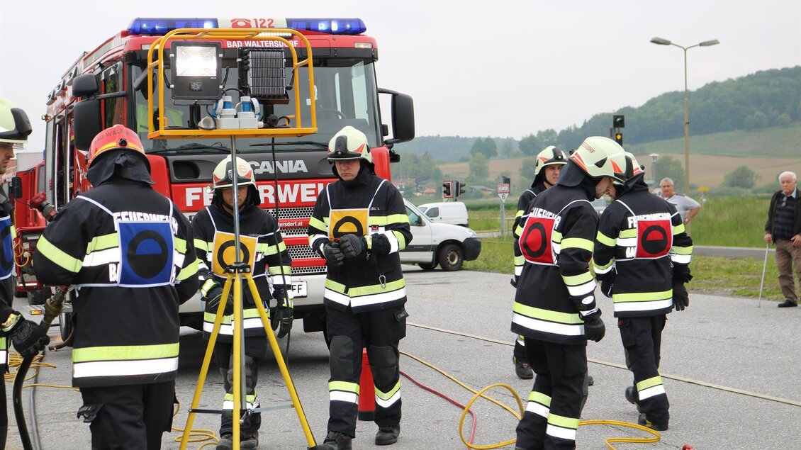 Feuerwehrleute in Schutzkleidung arbeiten an einem Einsatzort. Im Hintergrund ist ein Feuerwehrfahrzeug zu sehen. | © FF Bad Walterdorf