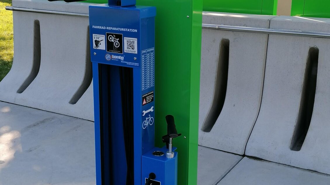 Eine Fahrradreparaturstation in leuchtendem Blau und Grün. Sie bietet verschiedene Werkzeuge zur Wartung von Fahrrädern. | © Thermen- & Vulkanland