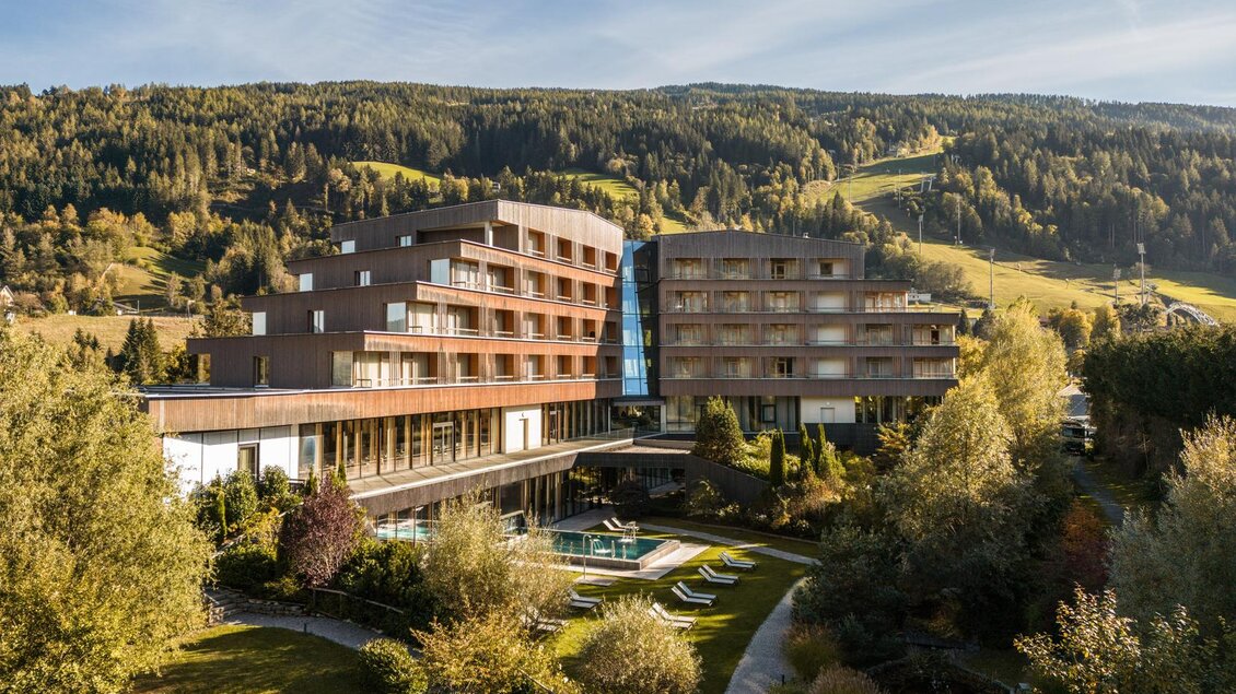 Ein modernes Hotel umgeben von grüner Landschaft und sanften Hügeln. Der Außenbereich verfügt über einen Pool und Liegen für entspannte Tage. | © Falkensteiner Hotel Schladming/ Fotograf Dragan Dokmanovic