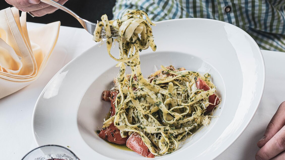 Ein Teller mit frischen Pasta und einer grünen Sauce. Im Vordergrund wird die Pasta mit einer Gabel aufgerollt. | © Anna Ullrich