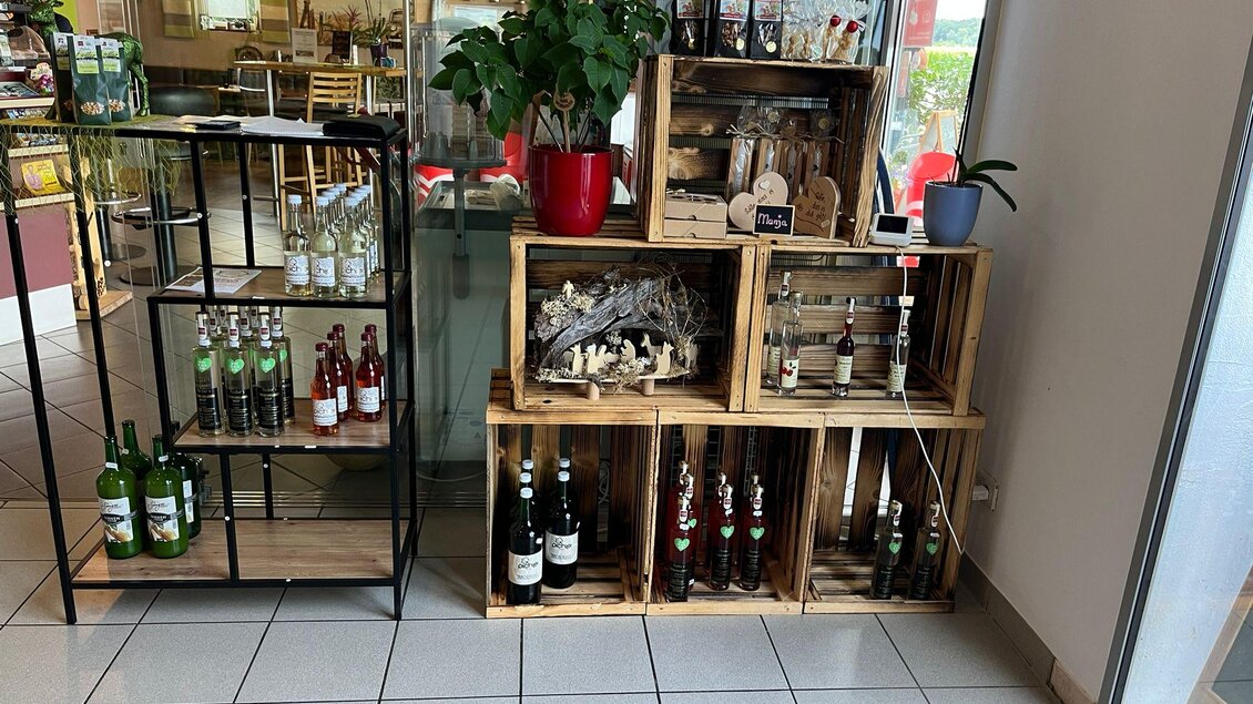 Ein Verkaufsbereich mit Holzkisten, die verschiedene Getränke präsentieren. Rechts sind Flaschen und dekorative Elemente in einer hellen Umgebung zu sehen. | © Bettina Fiedler