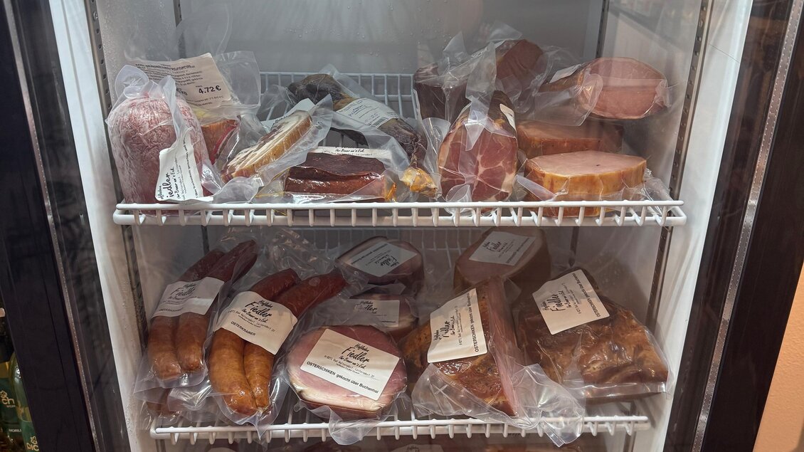 Ein Kühlschrank mit verschiedenen verpackten Lebensmitteln, darunter Wurst, Käse und Gebäck. Die Artikel sind übersichtlich angeordnet und mit Etiketten versehen. | © Sonja Brünner