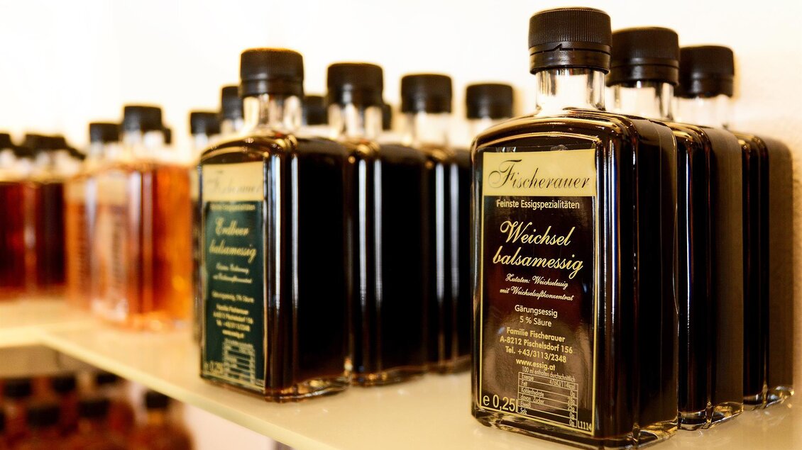 Eine Reihe von Flaschen mit Balsamico-Essig steht auf einem Regal. Die Flaschen sind unterschiedlich gefüllt und haben ansprechende Etiketten. | © Tourismusverband Oststeiermark