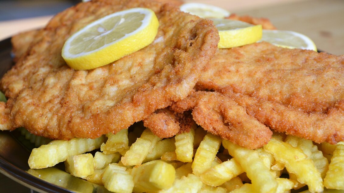 Zu sehen ist ein Wiener Schnitzel als Hauptgang mit einer Zitrone garniert.  | © Flourl's Schenke