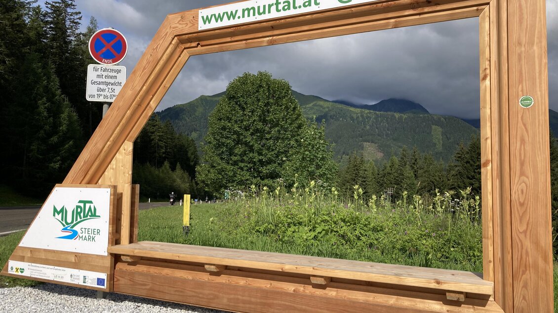 Ein großer Holzrahmen mit der Aufschrift „Murtal“ steht in der Natur. Im Hintergrund sind grüne Berge und Bäume zu sehen. | © Erlebnisregion Murtal