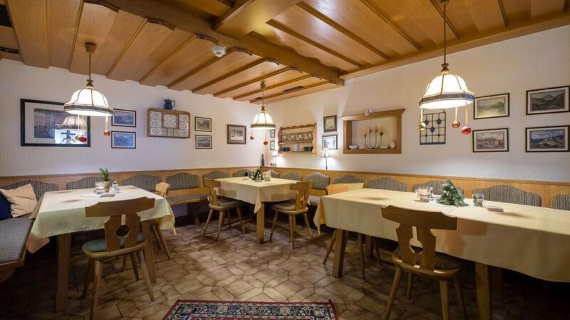 Ein gemütliches Restaurant mit Holztischen und Bänken. Die Wände sind mit Bildern geschmückt und es gibt sanfte Beleuchtung. | © Gasthof Bartelbauer / Fred Lindmoser