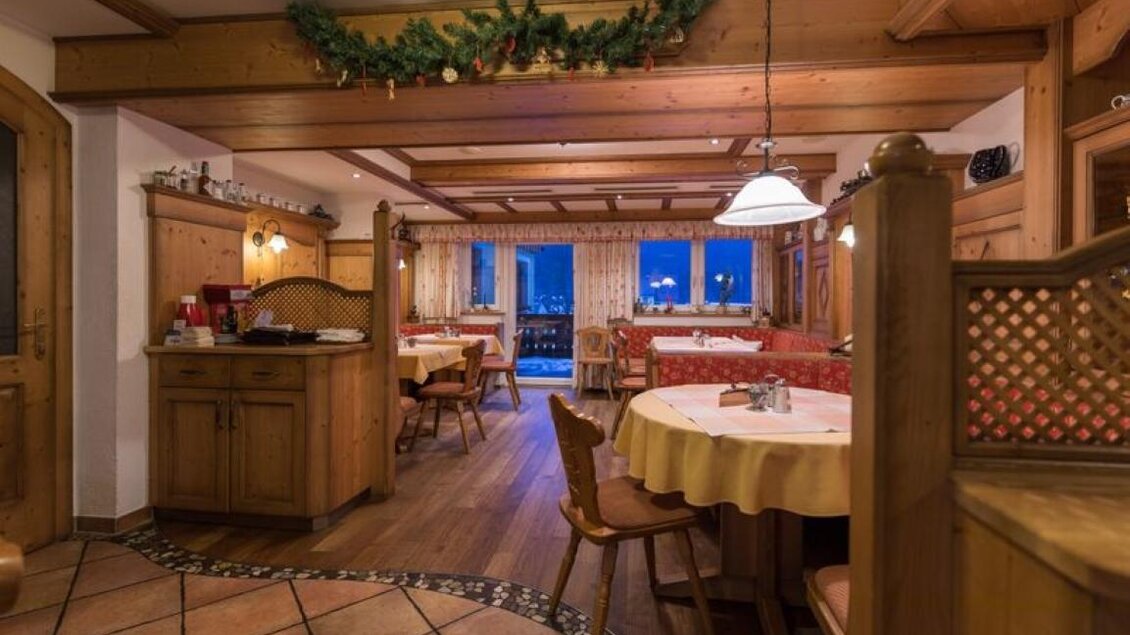 Ein gemütliches Restaurant mit Holzmöbeln und warmem Licht. Große Fenster bieten einen Blick auf die Abendstadt. | © Gasthof Bartelbauer / Fred Lindmoser