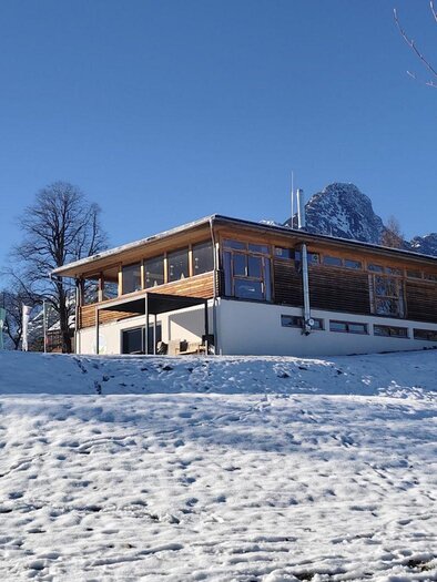 Ein modernes Holzhaus in einer verschneiten Landschaft. Der klare blaue Himmel bildet einen schönen Kontrast zur winterlichen Umgebung. | © Elisabeth Pichler