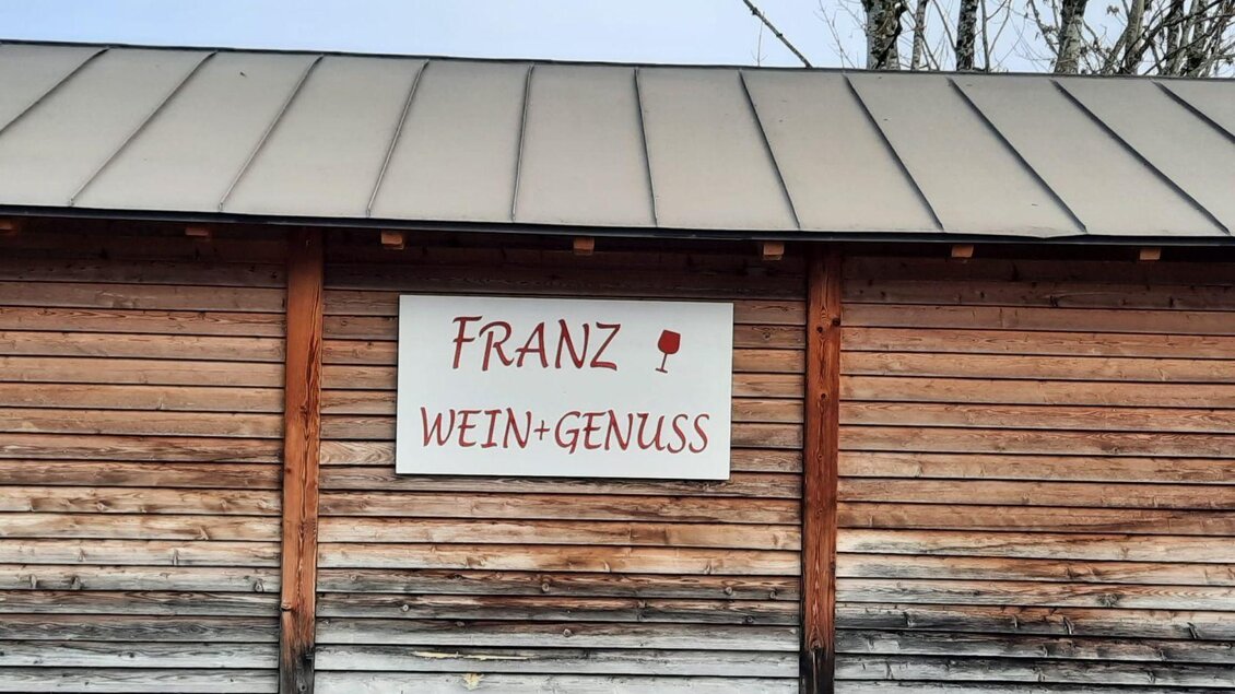 Ein Holzgebäude mit einem Schild. Auf dem Schild steht "Franz Wein+Genuss". | © Elisabeth Pichler