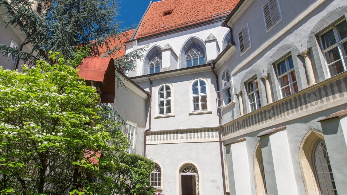 Begrünter Innenhof mit gotischen Fenstern im Franziskanerkloster Graz | © Graz Tourismus-Harry Schiffer
