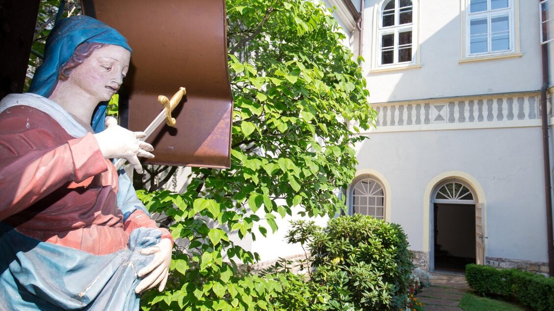 Marienstatue mit Schwert im grünen Innenhof des Franziskanerklosters Graz | © Graz Tourismus-Harry Schiffer