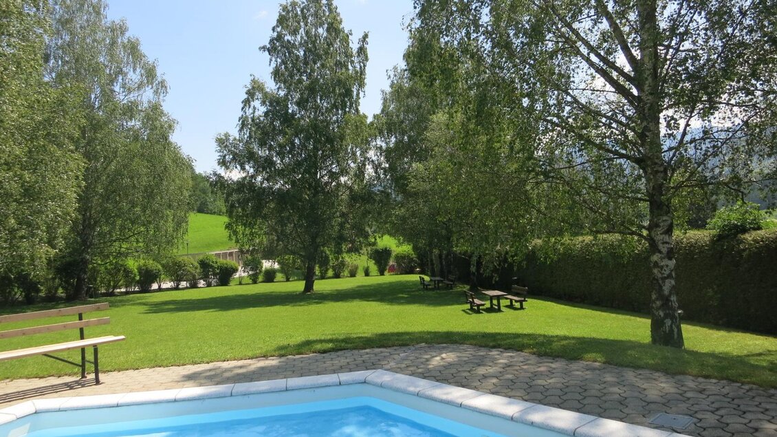 Ein einladender Garten mit einem Swimmingpool und vielen Bäumen. Im Hintergrund sind grüne Wiesen und eine entspannende Atmosphäre zu sehen. | © Gemeinde Mitterberg-Sankt Martin 